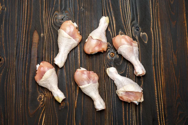 Pernas de frango cru em assadeira em um fundo de madeira — Fotografia de Stock
