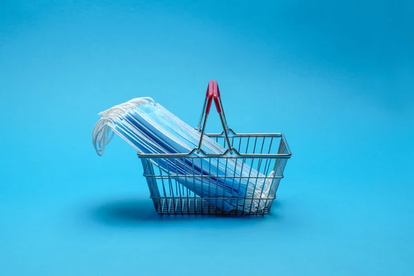 安全和网上购物检疫的概念。蓝色背景下有防护口罩的购物篮 — 图库照片