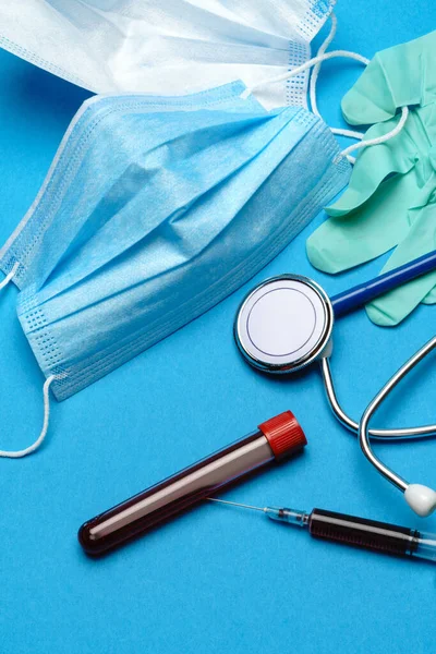 푸른 배경에 있는 의료 장비와 도구들 - 청진기, 수술용 마스크, 의료용 장갑, 주사기 및 시험관 건강 관리 및 의약품 개념 — 스톡 사진