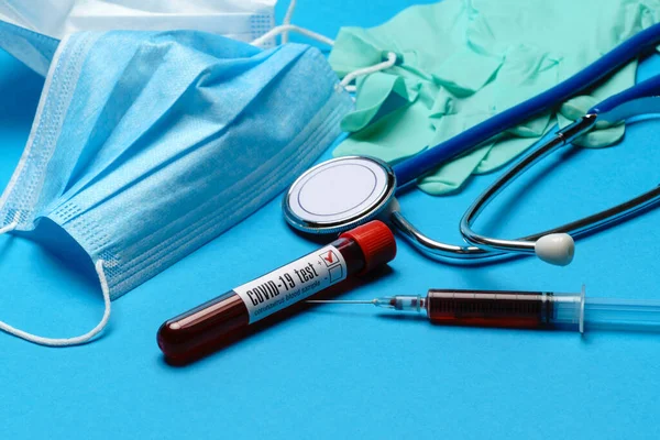 Draufsicht auf medizinische Geräte und Werkzeuge auf blauem Hintergrund - Stethoskop, Chirurgenmaske, medizinische Handschuhe, Spritze und Reagenzglas - Gesundheits- und Medizinkonzept — Stockfoto