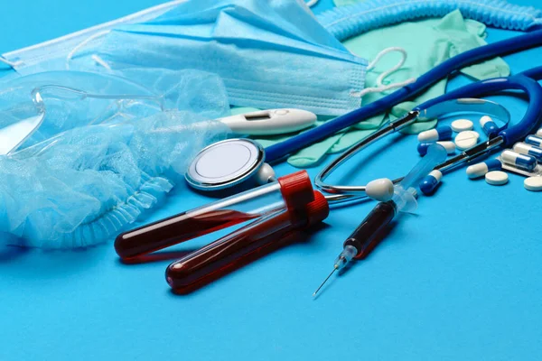 푸른 배경에 있는 의료 장비와 도구들 - 청진기, 수술용 마스크, 의료용 장갑, 주사기와 혈액 검사 튜브 - 건강 관리 및 의약품 개념 — 스톡 사진