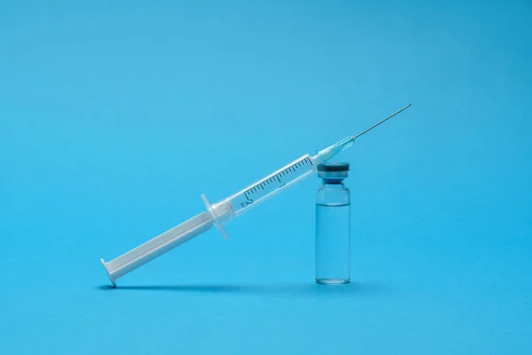 Medical vaccine ampoule and syringe over blue background — Stock Photo, Image