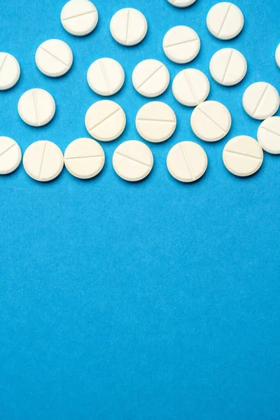 Groupe de pilules blanches ou comprimés sur fond bleu — Photo