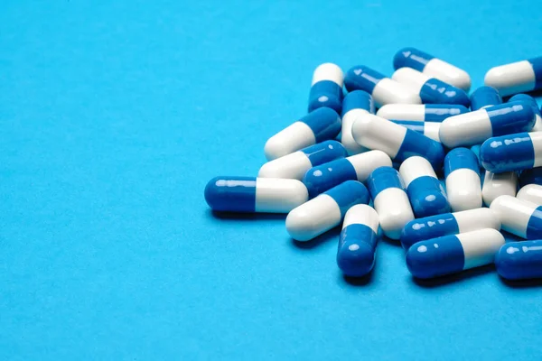 Skupina pilulek nebo kapslí na modrém pozadí — Stock fotografie