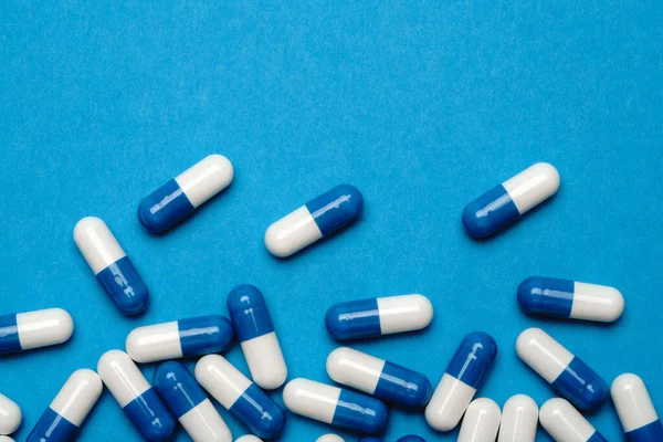 Skupina pilulek nebo kapslí na modrém pozadí — Stock fotografie