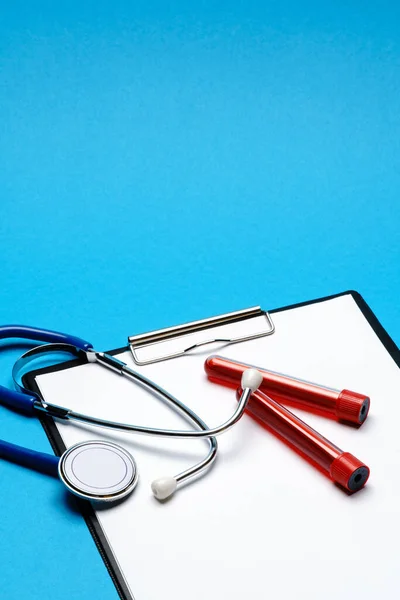 Zdravotní koncepce - stetoskop, zkumavka na krevní testy a schránka s prázdným listem — Stock fotografie