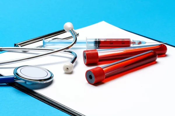 Zdravotní koncepce - stetoskop, zkumavka, injekční stříkačka a zásobník s prázdným listem — Stock fotografie