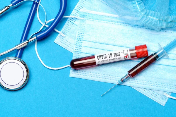 医学实验室概念-蓝色背景试管和注射器中的Covid-19血样 — 图库照片