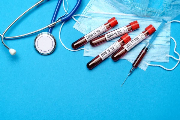 Conceito de laboratório médico - Grupo de amostras de sangue Covid-19 em tubos de ensaio e seringa sobre fundo azul — Fotografia de Stock