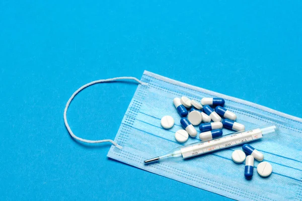 Védő orvosi arcmaszk, hőmérő és tabletták kék alapon - Felülnézet másolási hellyel — Stock Fotó