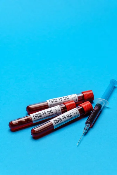 Syringe and Plastic Test Tube With Blood Sample over blue background with copyspace — 스톡 사진