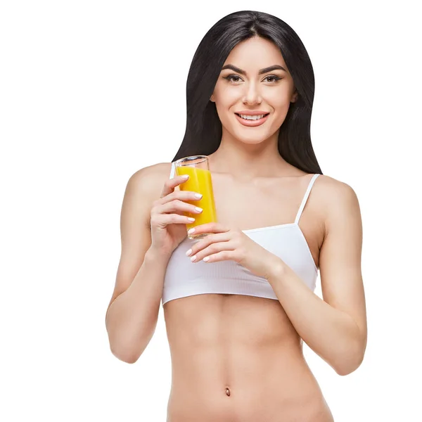 Sportowa kobieta na szarym tle trzymająca szklankę soku pomarańczowego — Zdjęcie stockowe