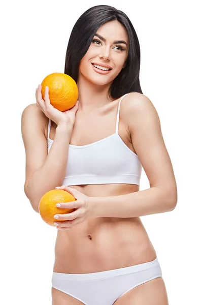 Studio skott av attraktiv ung kvinna med vacker kropp håller orange isolerad på vit — Stockfoto
