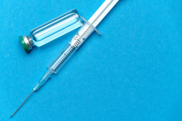 Spruta och ampuller med läkemedel eller vaccin över blå bakgrund — Stockfoto