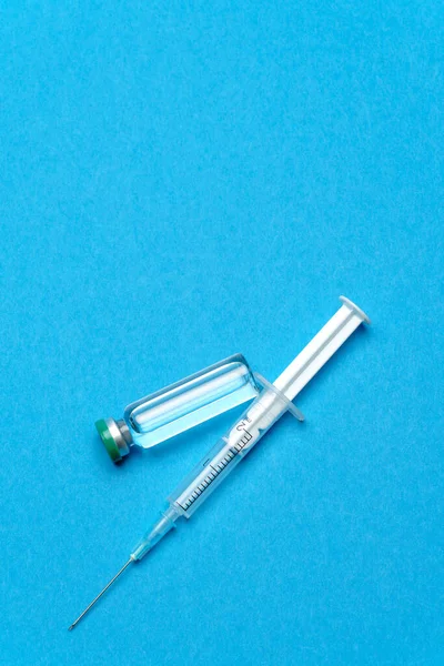 Syringe and ampoules with medicines or vaccine over blue background — Stock Photo, Image