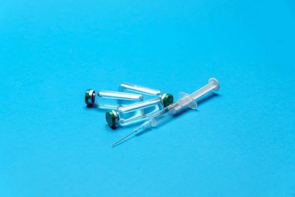 Syringe and ampoules with medicines or vaccine over blue background — Stock Photo, Image