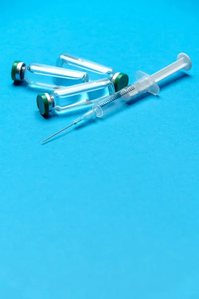 Syringe and ampoules with medicines or vaccine over blue background — Stock Photo, Image