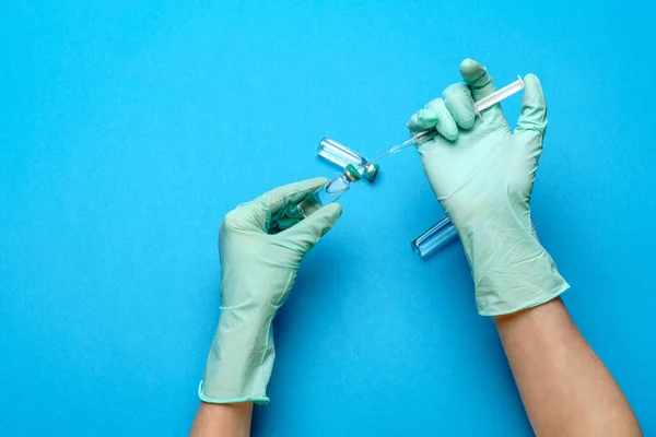 Asistente técnico del laboratorio o médico que usa guantes de goma o látex que sostienen una ampolla con medicamento o vacuna y jeringa —  Fotos de Stock