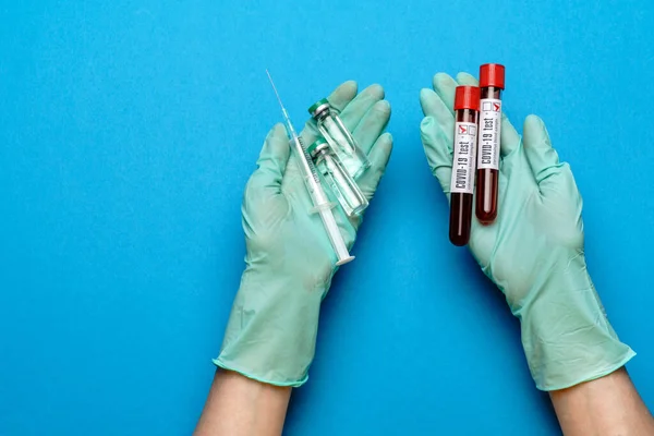 Labortechniker oder Arzt mit Gummi- oder Latexhandschuhen, die eine Ampulle mit Medikamenten oder Impfstoff und ein Reagenzglas mit Blutprobe enthalten — Stockfoto