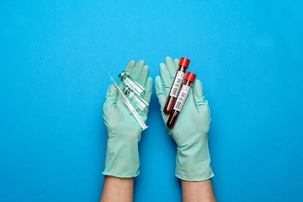 Asistente técnico del laboratorio o médico que usa guantes de goma o látex que sostienen una ampolla con medicamentos o vacunas y probeta con muestras de sangre — Foto de Stock