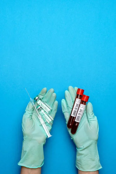 Assistente técnico de laboratório ou médico vestindo luvas de borracha ou látex segurando uma ampola com medicamento ou vacina e tubo de teste com amostra de sangue — Fotografia de Stock