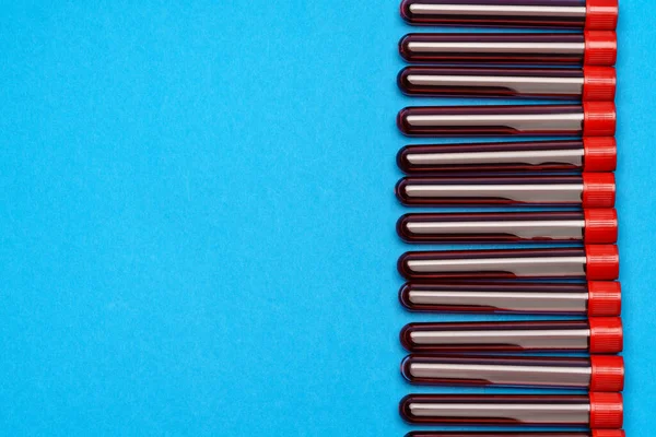 Cadre fait de tubes à essai de médecine avec des échantillons de sang sur fond bleu — Photo