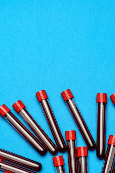 Top view of medicine test tubes with blood samples over blue background — Stock Photo, Image