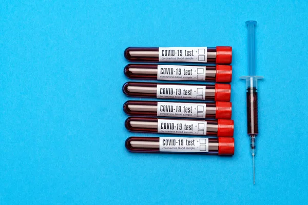 Vista dall'alto delle provette di medicina con campioni di sangue e siringa su sfondo blu — Foto Stock