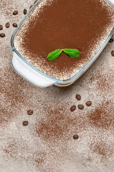 Dessert italien traditionnel Tiramisu dans un plat de cuisson en verre sur fond de béton — Photo