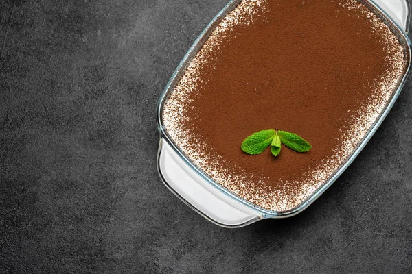 Dessert italien traditionnel Tiramisu dans un plat de cuisson en verre sur fond de béton — Photo