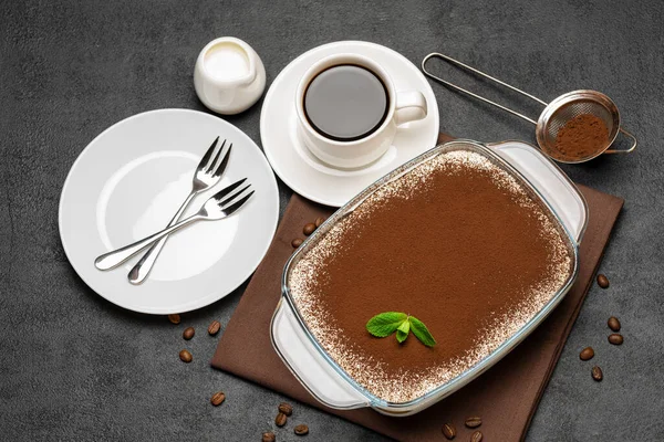 Traditionele Italiaanse Tiramisu dessert in glazen bakvorm en kopje verse hete espresso koffie op betonnen achtergrond — Stockfoto