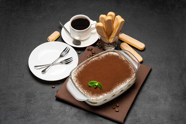 Traditionele Italiaanse Tiramisu dessert in glazen bakvorm, kopje verse hete espresso koffie en savoiardi koekjes op betonnen achtergrond — Stockfoto