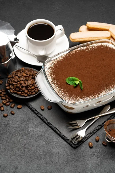 Traditionele Italiaanse Tiramisu dessert in glas bakplaat, koffiezetapparaat, savoiardi koekjes en een kopje verse hete espresso koffie op beton achtergrond — Stockfoto