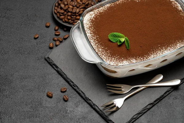 Traditioneel Italiaans Tiramisu dessert in glazen bakvorm op stenen dienblad op betonnen ondergrond — Stockfoto