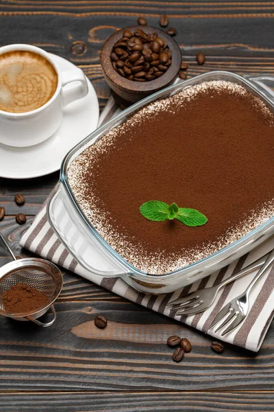 Traditionele Italiaanse Tiramisu dessert in glazen bakvorm en kopje verse hete espresso koffie op houten achtergrond — Stockfoto