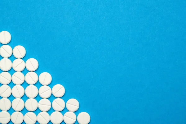 Groupe de pilules rondes blanches sur fond bleu — Photo