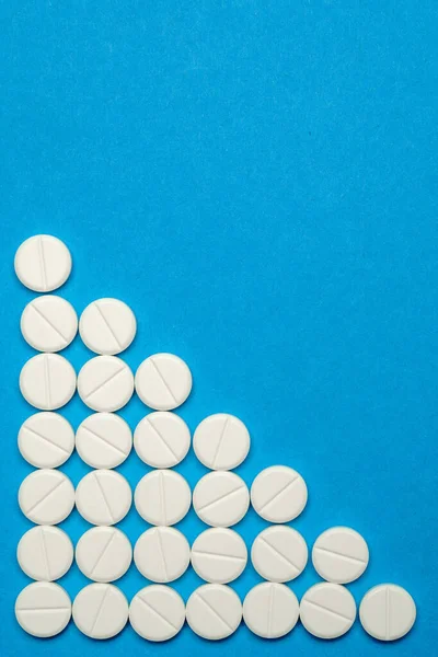Groupe de pilules rondes blanches sur fond bleu — Photo