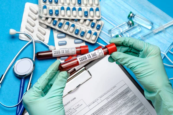 Labortechniker oder Arzt mit Gummi- oder Latexhandschuhen, die das Blutprobenröhrchen über Klemmbrett mit Blanko-Formular halten — Stockfoto