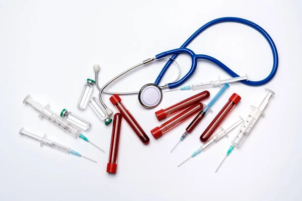 Ampullen voor medisch gebruik, reageerbuisjes, spuiten en stethoscoop over lichtgrijze of witte achtergrond — Stockfoto