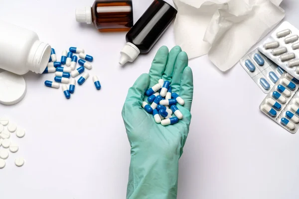 Close up doctor hand in a latex glove holding capsules pills over light grey or white background with medical suppliements — Stock Photo, Image