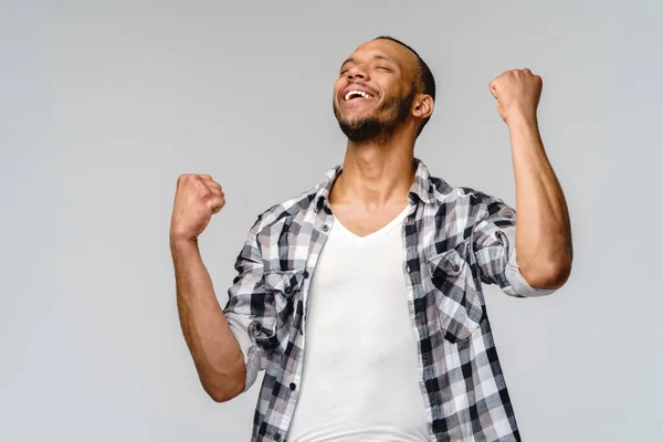 Giovane uomo afroamericano sì vincere gesticolando su sfondo grigio chiaro — Foto Stock