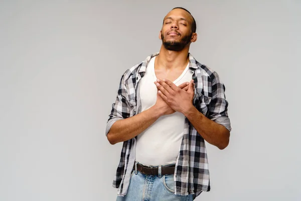 Happy pleased african-american man holding hands on chest to heart feeling love appreciation gratitude honesty — Stockfoto