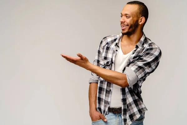 Joyful amigável afro-americano jovem iwearing camisa casual apontando por dedo para espaço de cópia vazio — Fotografia de Stock