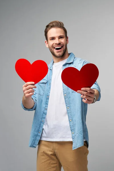 Portrait de charmant homme tenir main papier carte en forme de coeur porter chemise style décontracté isolé sur fond gris — Photo