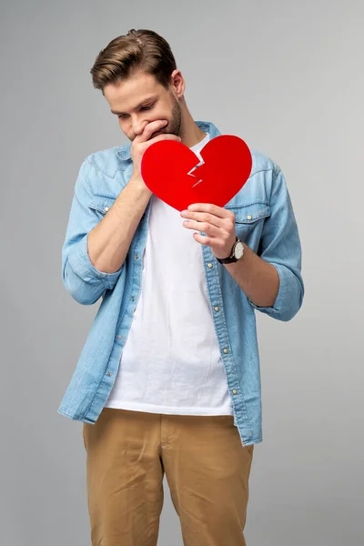 Kırık kağıt tutan yakışıklı genç adam Gri arka planda duran kırmızı sevgililer günü kalbi — Stok fotoğraf