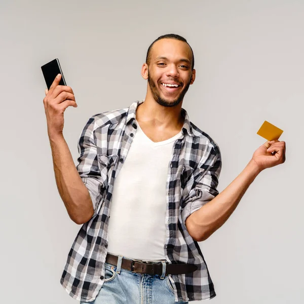 Ritratto di un giovane afroamericano in possesso di cellulare e carta di credito o di sconto — Foto Stock