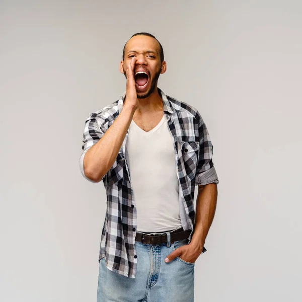 Joven afroamericano hombre gritando sobre un fondo gris —  Fotos de Stock