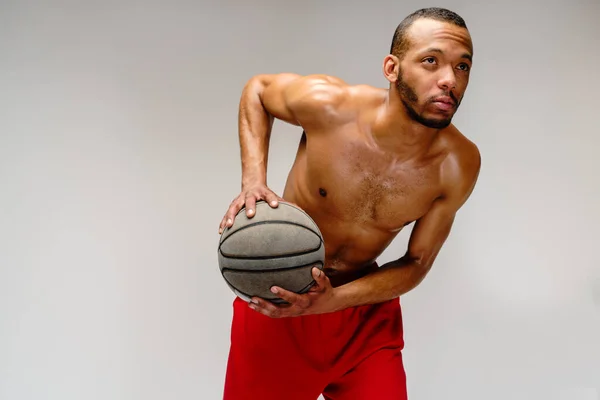 Muscular Africano americano desportista jogar basquete merdoso sobre luz cinza fundo — Fotografia de Stock