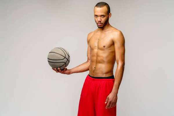 Muscular Africano americano desportista jogar basquete merdoso sobre luz cinza fundo — Fotografia de Stock