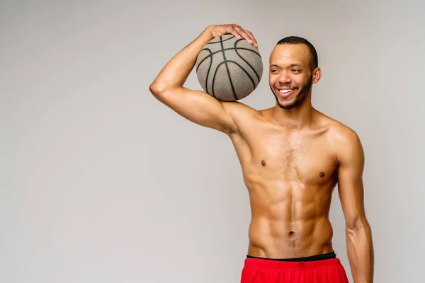 Muscular Africano americano desportista jogar basquete merdoso sobre luz cinza fundo — Fotografia de Stock